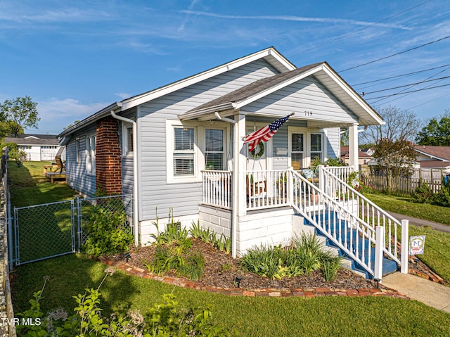 bungalow featuring covered porch, fence, a gate, and a front yard