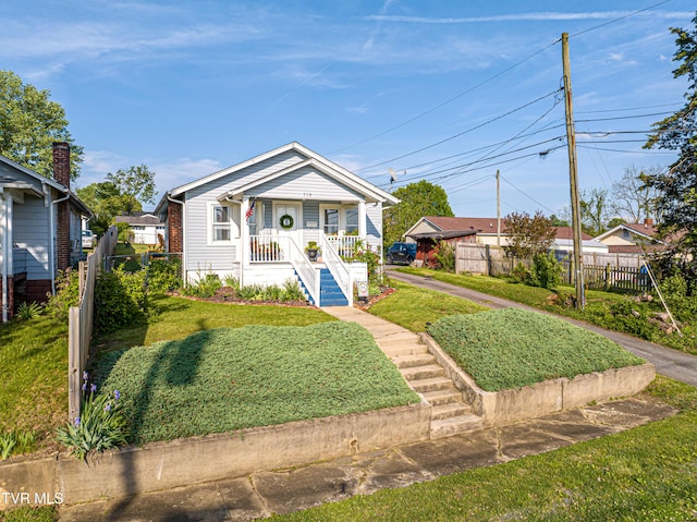bungalow with a porch, fence, a front yard, and stairway