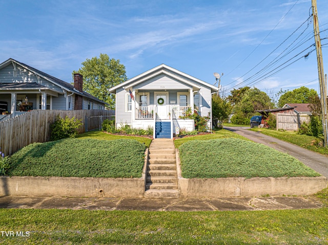 bungalow-style house with a porch, fence, stairs, and a front yard