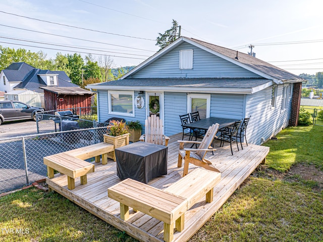 wooden deck featuring a lawn, fence, and outdoor dining space