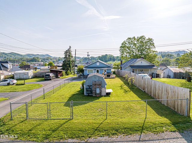 view of front of house with a fenced backyard, a storage shed, a mountain view, an outbuilding, and a residential view