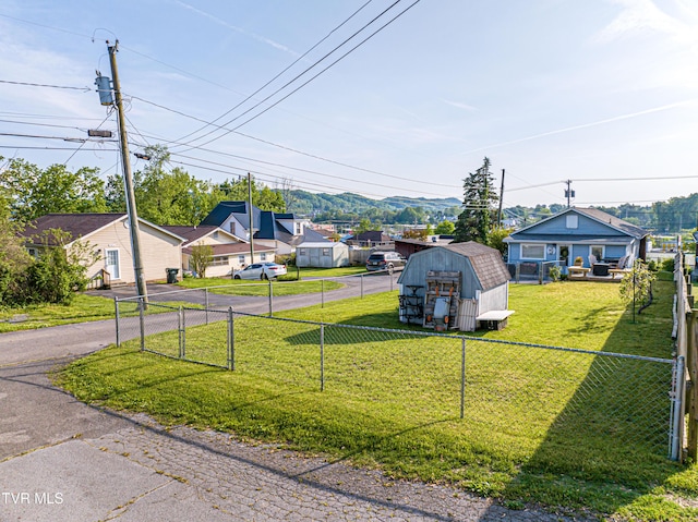 view of yard featuring an outdoor structure, driveway, a fenced backyard, and a storage unit