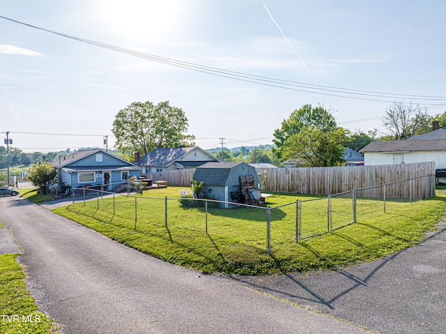 view of front of house with a gate, an outdoor structure, a fenced backyard, a front lawn, and a storage unit