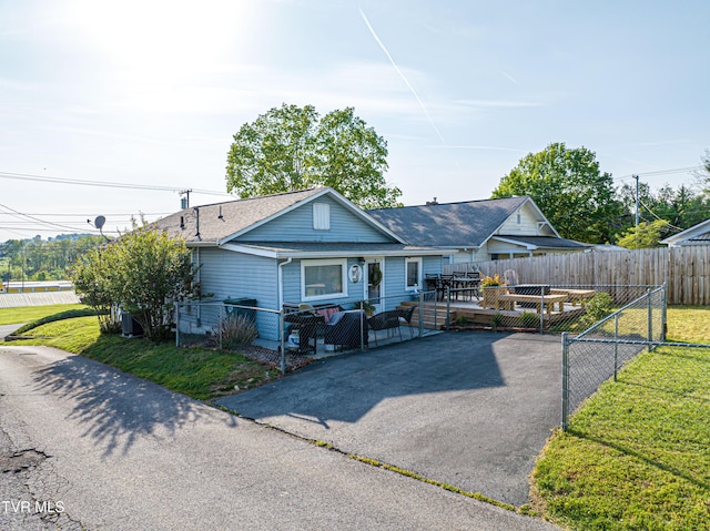 view of front of home with a fenced backyard, a front lawn, roof with shingles, and a deck