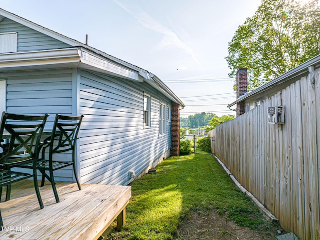 view of side of home featuring fence, a yard, and a deck