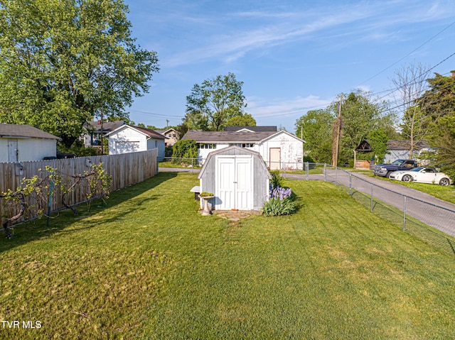 view of yard with a storage shed, an outbuilding, and a fenced backyard