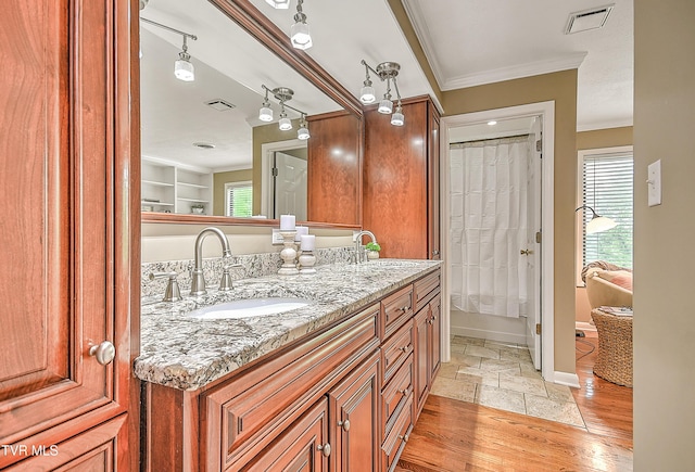 bathroom featuring wood finished floors, vanity, visible vents, crown molding, and baseboards