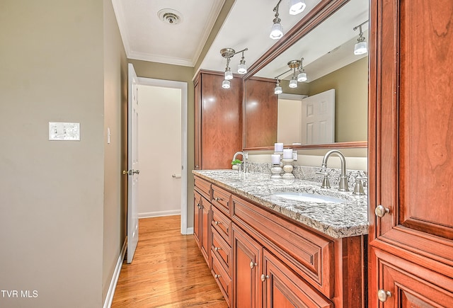 bathroom featuring wood finished floors, visible vents, baseboards, vanity, and ornamental molding