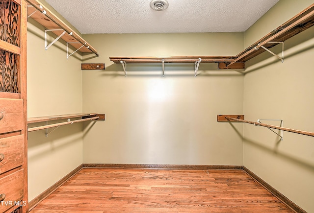 walk in closet with light wood finished floors and visible vents