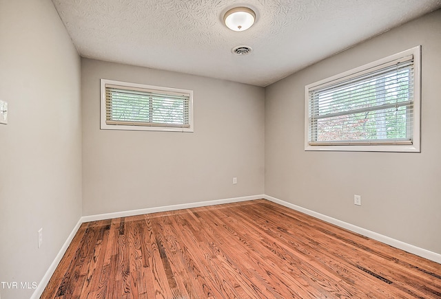 unfurnished room with baseboards, visible vents, and wood finished floors