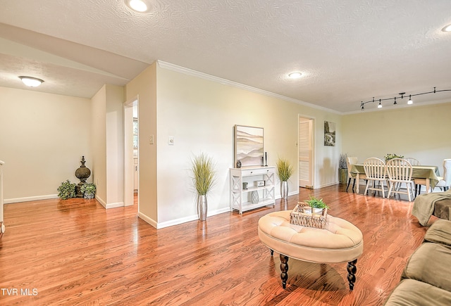 living room featuring ornamental molding, baseboards, recessed lighting, a textured ceiling, and light wood finished floors