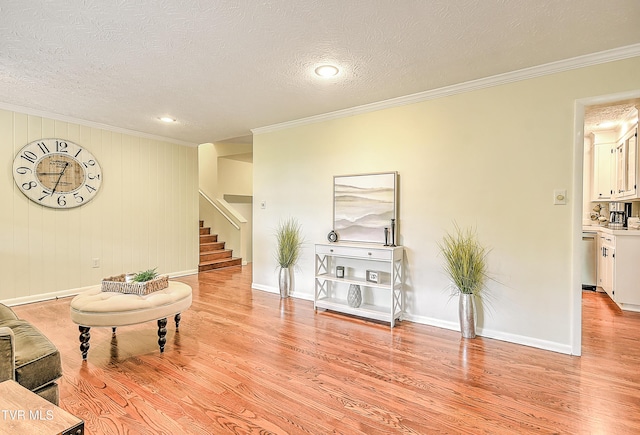 living area featuring crown molding, a textured ceiling, light wood-style flooring, and stairway