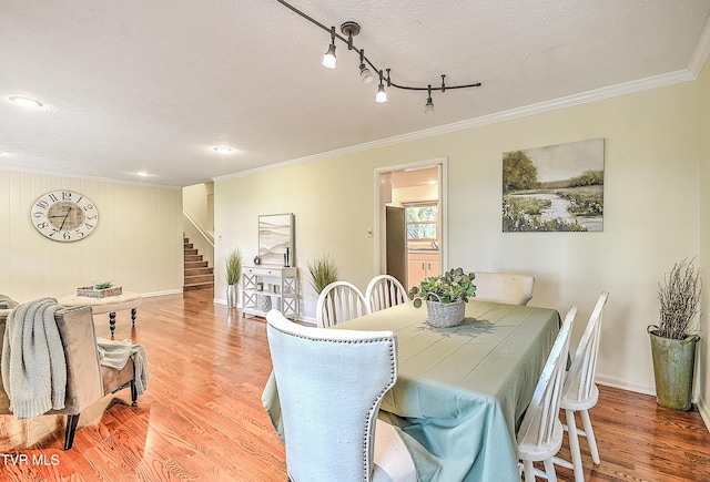 dining space featuring wood finished floors, recessed lighting, stairway, crown molding, and baseboards