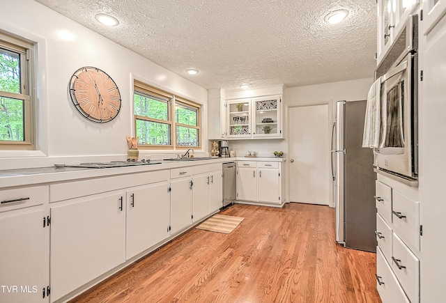 kitchen featuring a sink, stainless steel appliances, a textured ceiling, and white cabinetry