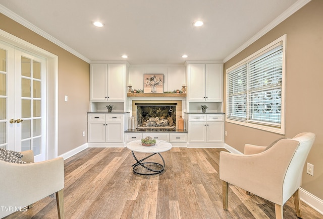 sitting room with baseboards, ornamental molding, and light wood-style floors