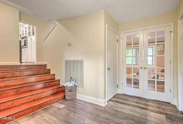 stairs featuring baseboards, visible vents, french doors, and wood finished floors