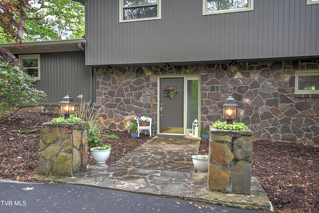 entrance to property featuring a patio area and stone siding