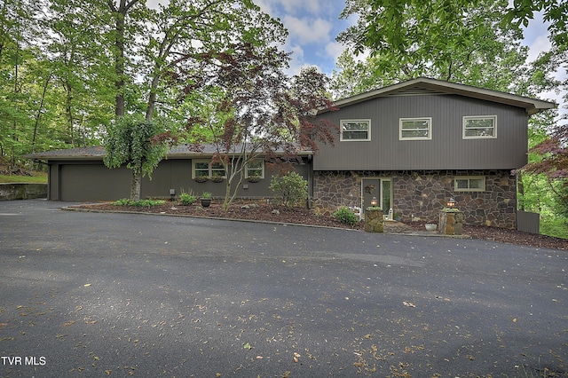 view of front of home with stone siding, aphalt driveway, and a garage