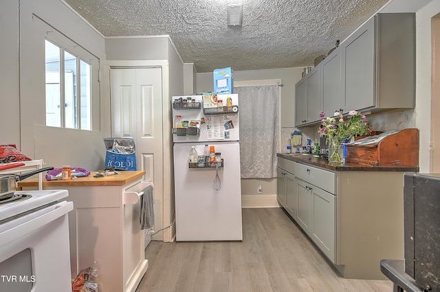921 E Sevier Ave, Kingsport, TN 37660 - kitchen with a textured ceiling, white appliances, light wood-type flooring, and gray cabinets