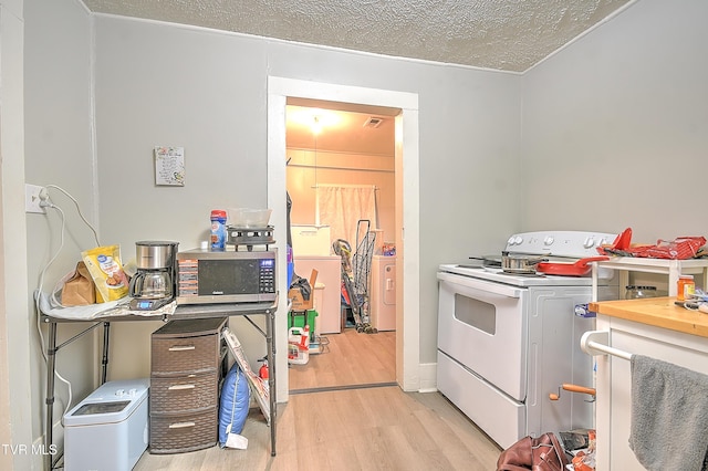 921 E Sevier Ave, Kingsport, TN 37660 - kitchen with a textured ceiling, white electric range oven, light wood-type flooring, and washer / dryer