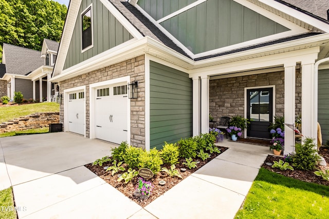 view of home's exterior featuring board and batten siding, stone siding, a garage, concrete driveway, and roof with shingles