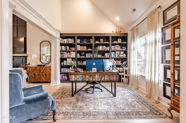 office area featuring wood finished floors, high vaulted ceiling, and decorative columns