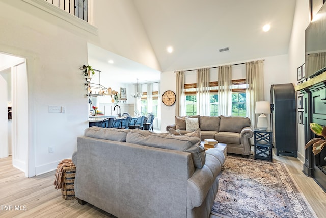 living room featuring light wood finished floors, high vaulted ceiling, and recessed lighting