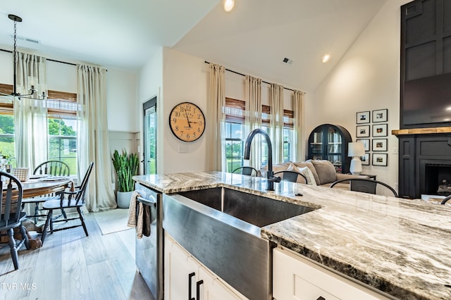 kitchen with light stone countertops, a sink, stainless steel dishwasher, high vaulted ceiling, and white cabinets