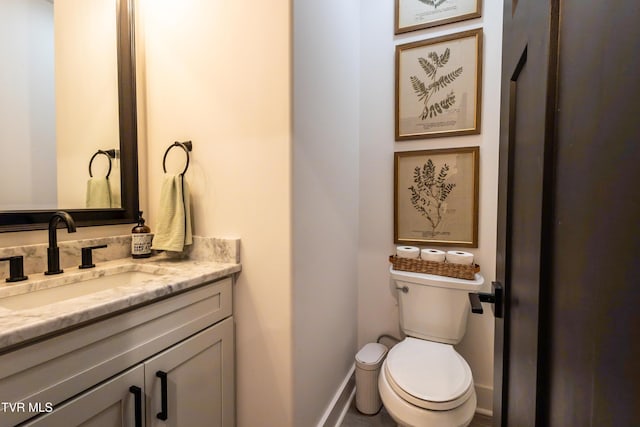 half bathroom with toilet, vanity, and baseboards