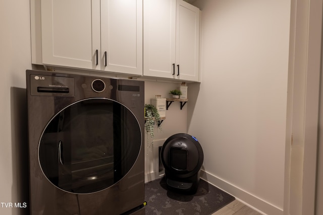 laundry area with washer / dryer, cabinet space, baseboards, and wood finished floors