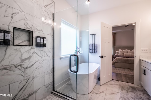 ensuite bathroom with marble finish flooring, a freestanding bath, healthy amount of natural light, and vanity