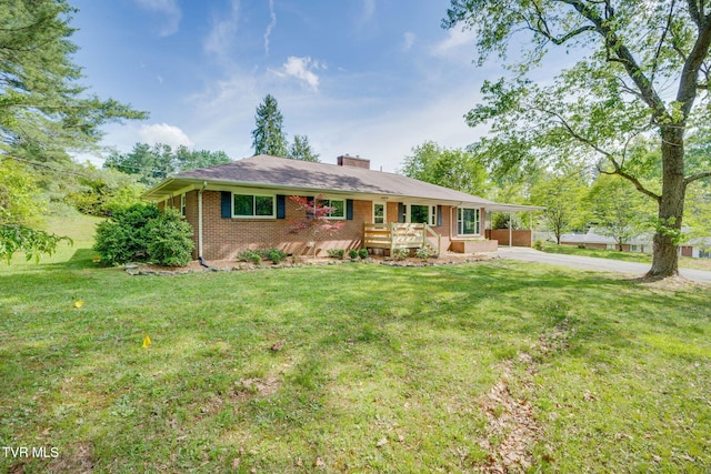 single story home with a carport, concrete driveway, a front yard, and brick siding