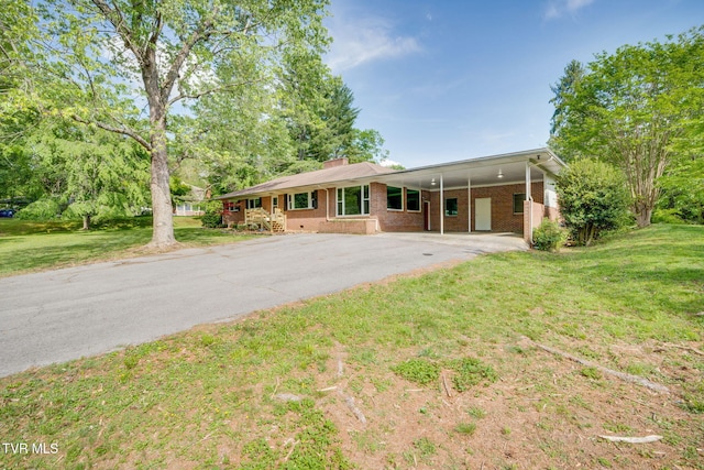 view of front of property featuring brick siding, aphalt driveway, a chimney, and a front yard