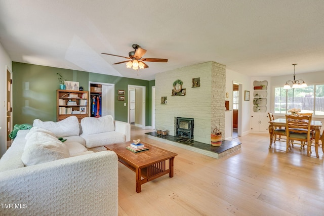 living area featuring baseboards, ceiling fan with notable chandelier, and light wood-style flooring