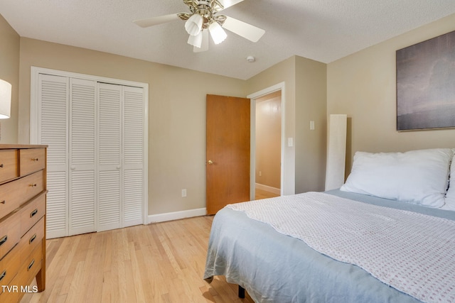 bedroom featuring light wood-style floors, baseboards, ceiling fan, and a closet