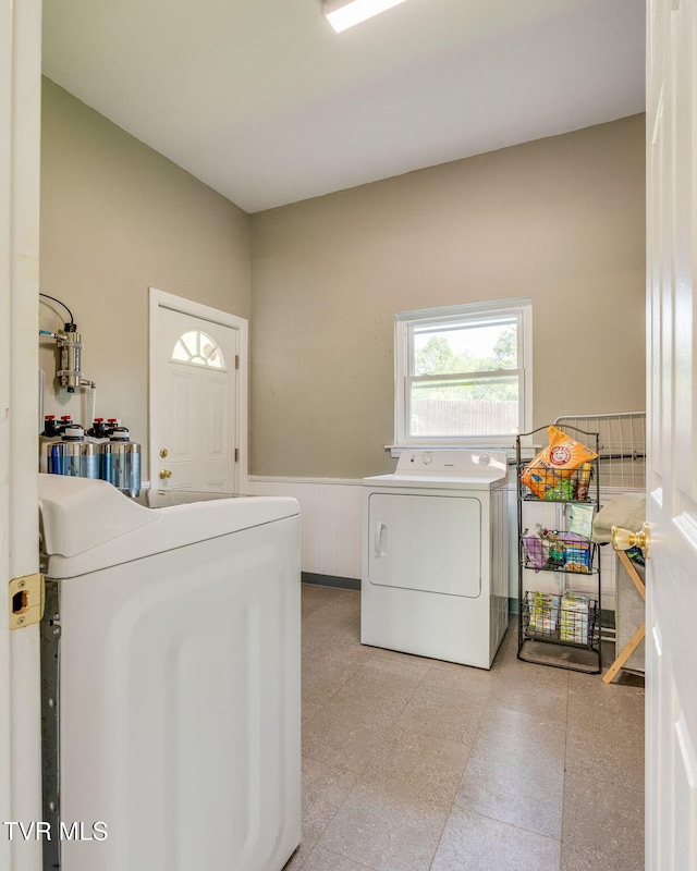 washroom featuring washing machine and clothes dryer, laundry area, and a wainscoted wall