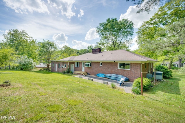 back of property with brick siding, a patio, a yard, and a chimney
