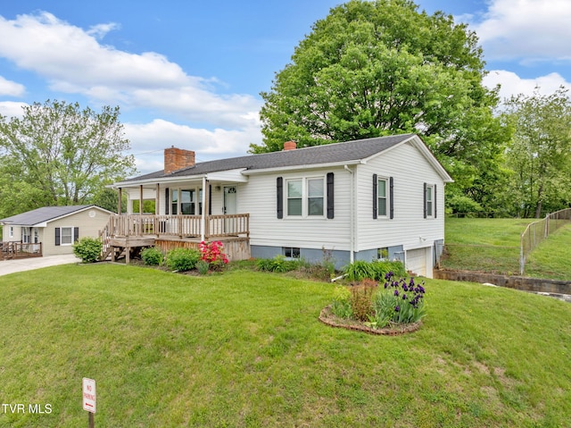view of front of house with a chimney, fence, covered porch, a garage, and a front yard