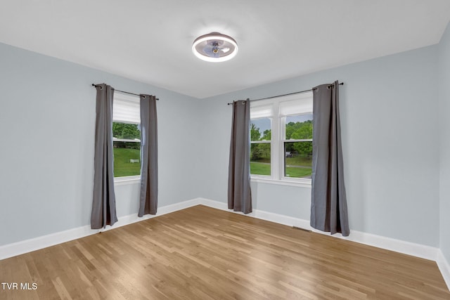 empty room with baseboards, light wood finished floors, and visible vents