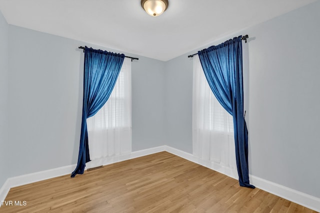 spare room with baseboards and light wood-style floors