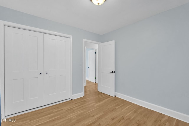 unfurnished bedroom with baseboards, light wood-type flooring, and a closet