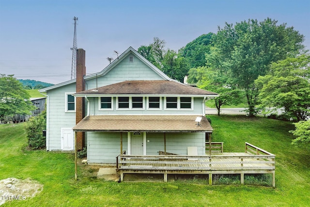 back of property with a lawn, a chimney, a wooden deck, and a shingled roof
