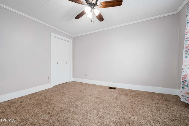 carpeted spare room featuring ceiling fan, ornamental molding, baseboards, and visible vents