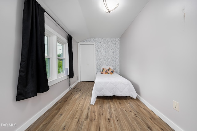 bedroom with wood finished floors, baseboards, and lofted ceiling