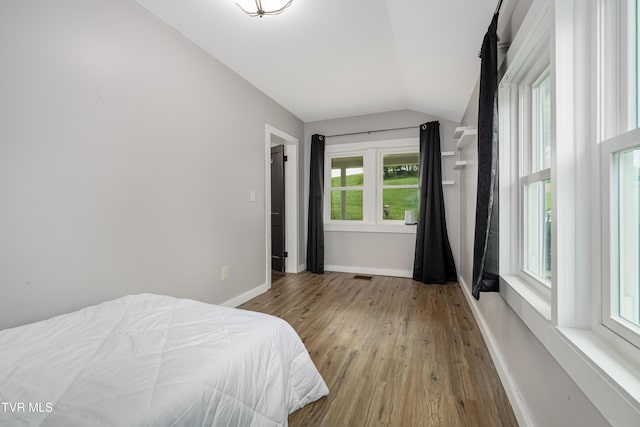 bedroom with baseboards, wood finished floors, lofted ceiling, and visible vents