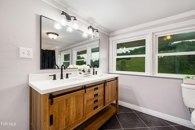 bathroom with a sink, double vanity, toilet, and tile patterned floors