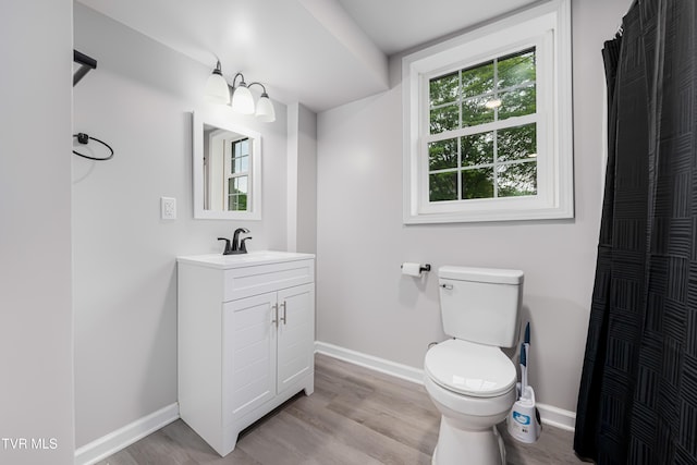 bathroom with toilet, baseboards, vanity, and wood finished floors