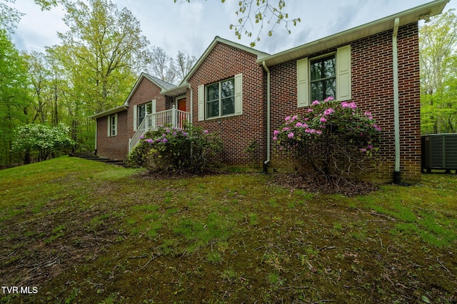 view of home's exterior featuring central air condition unit, brick siding, and a lawn
