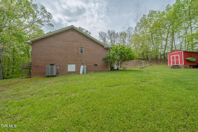 view of home's exterior featuring a storage shed, an outdoor structure, brick siding, a yard, and cooling unit