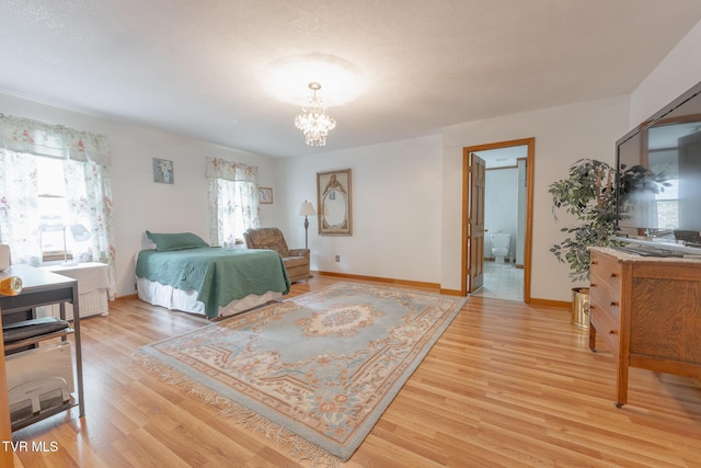 bedroom with a notable chandelier, light wood-type flooring, and baseboards